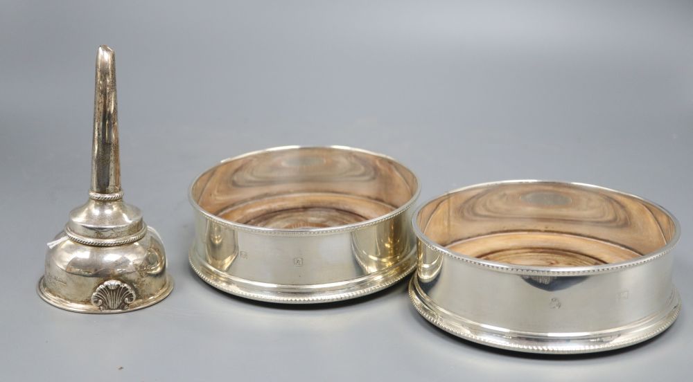 A pair of bottle coasters with beaded rims and turned hardwood bases, London 1991, width 14cm and a George III style wine funnel